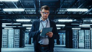 A person walking through a data center with a tablet