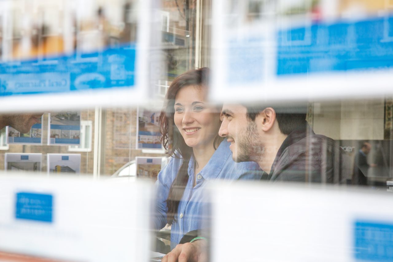 Two people look inside estate agent window