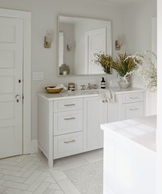 White bathroom with tiles floor, cabinetry, mirror