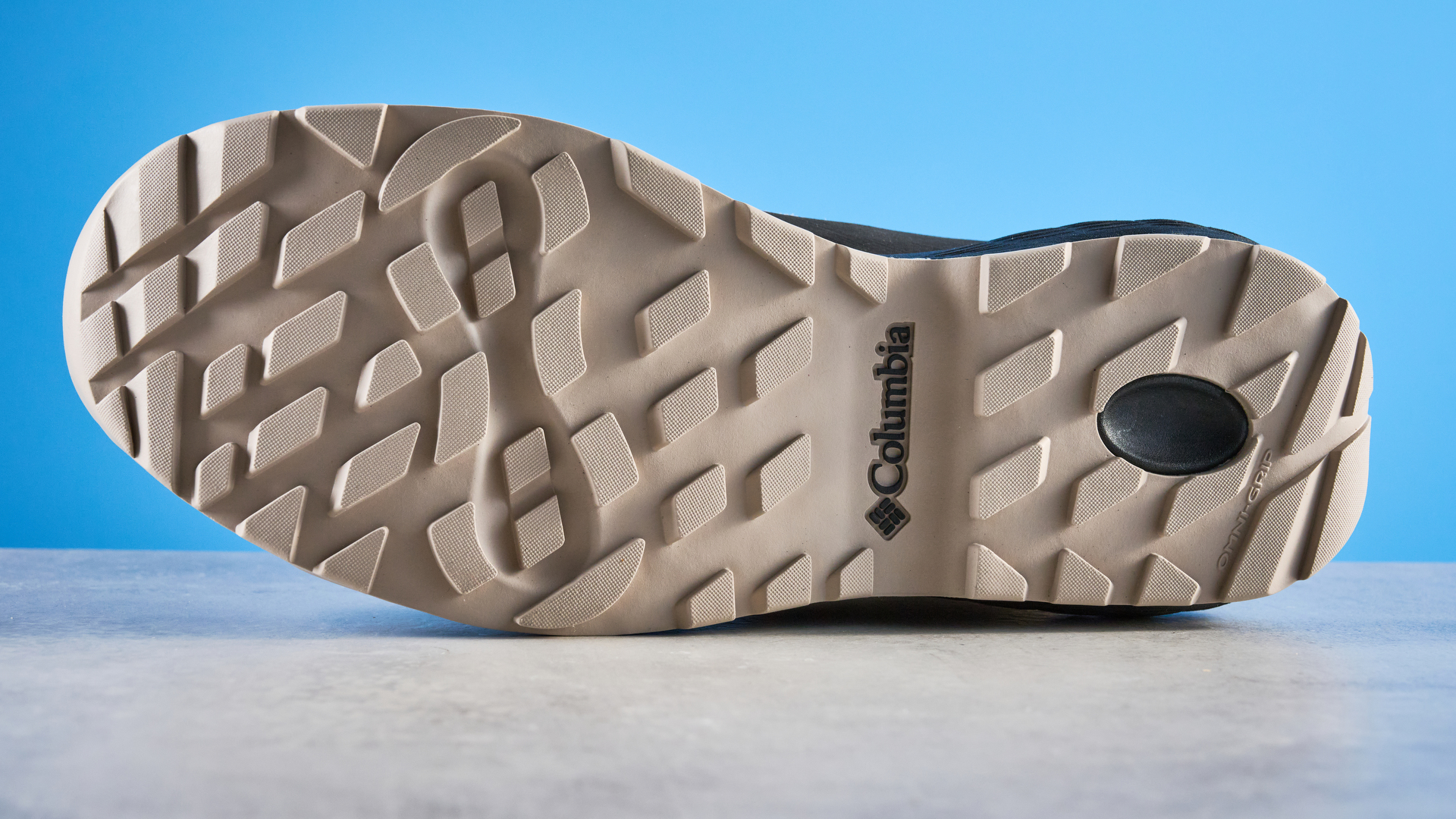The Columbia Newton Alpine sole on a stone surface with a blue background