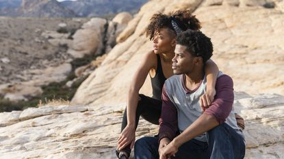 A couple rests and enjoys the view after hiking to a mountaintop.