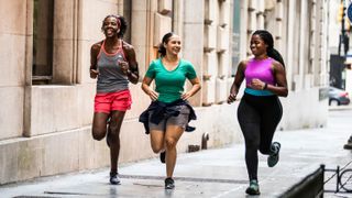 three women running down a street together