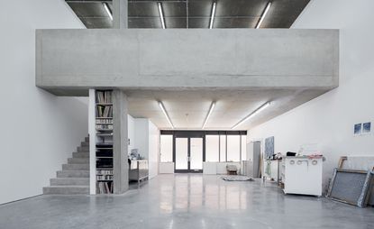 Michael Raedecker’s studio, featuring a polished concrete floor. The architects installed stairs to the mezzanine, created storage in the supporting pillar and tucked a kitchen away behind it