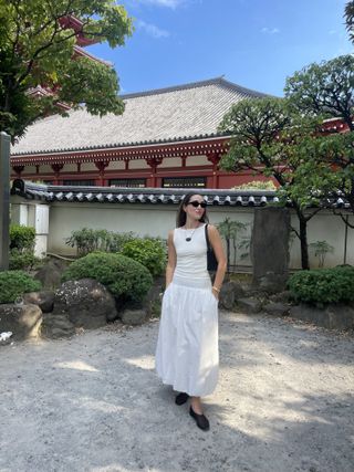 Anna LaPlaca wearing a white Reformation Dusk top, Free People bubble-hem maxi skirts, black mesh flats, and a Heaven Mayhem cord necklace