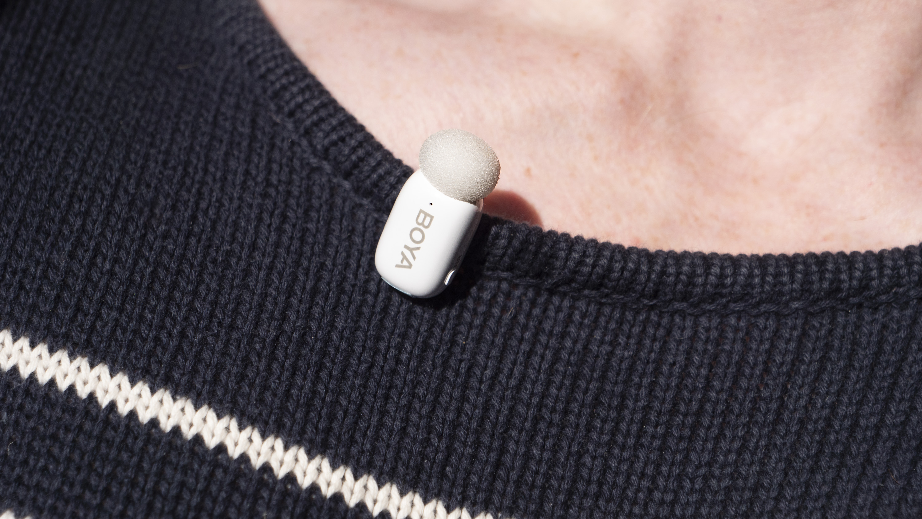 Boya Mini wireless mic clipped to a person's navy sweater