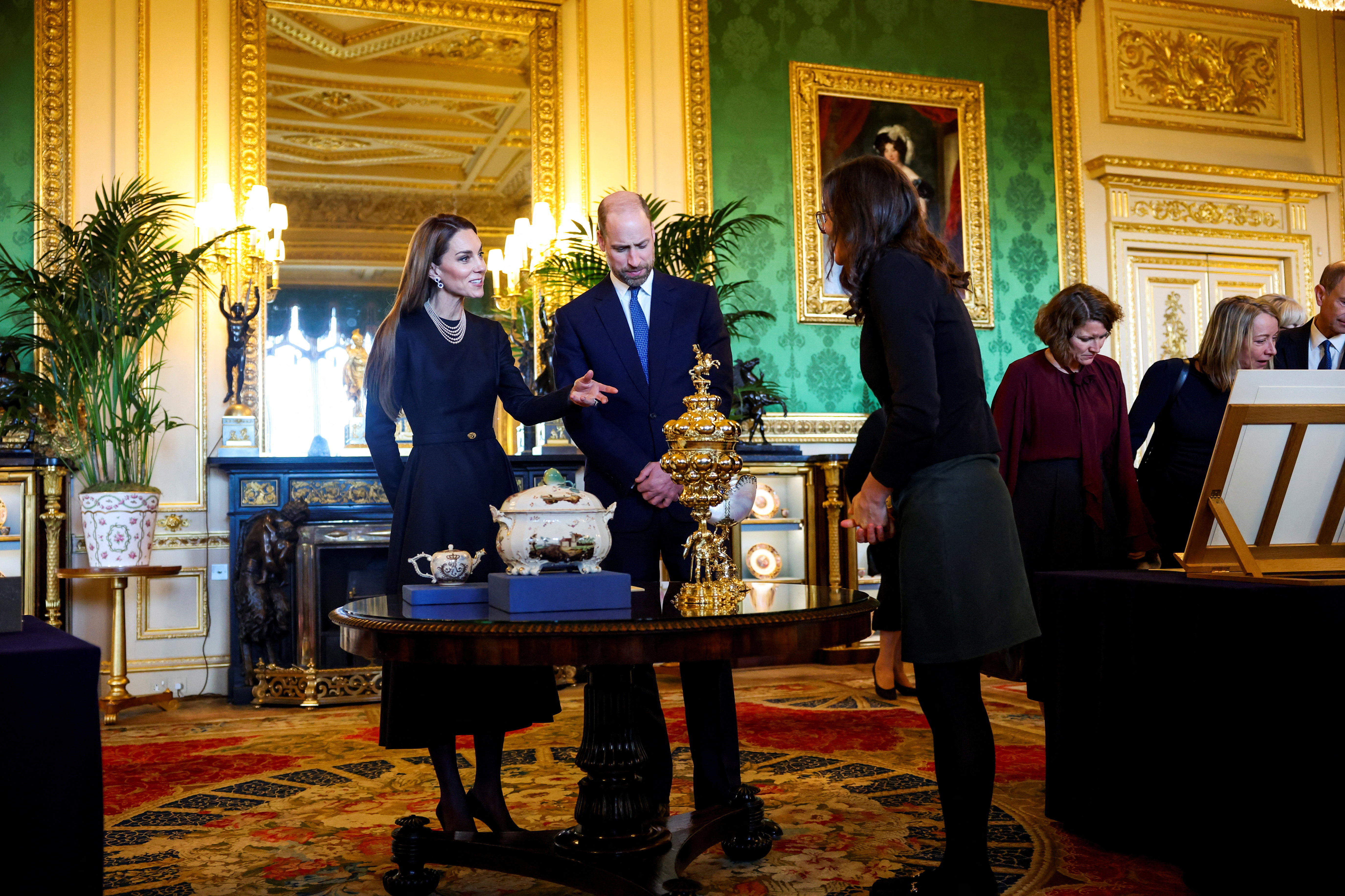 Princess Kate and Prince William standing at a table and speaking to a woman at Windsor Castle