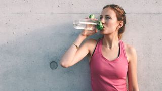 Woman drinking water from bottle before a workout