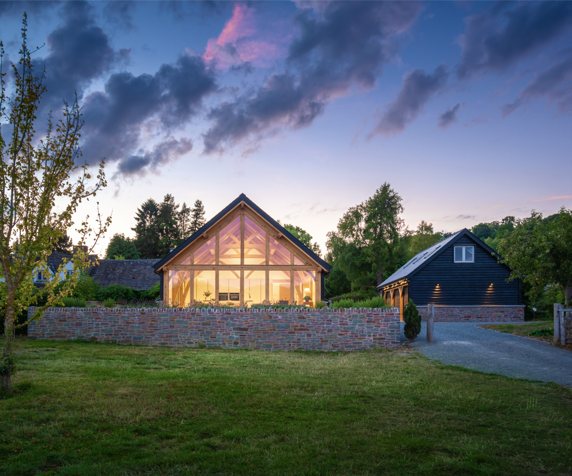 single storey timber frame house with glazed gable end and timber frame garage to side with rooms above