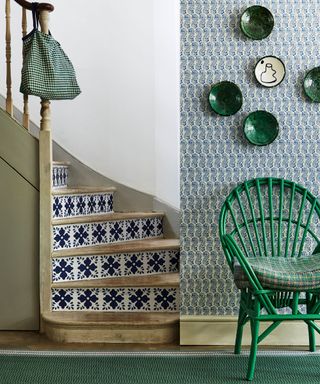 Blue and green scheme, blue painted tiled staircase, patterned blue wallpaper with green chair and green accessories
