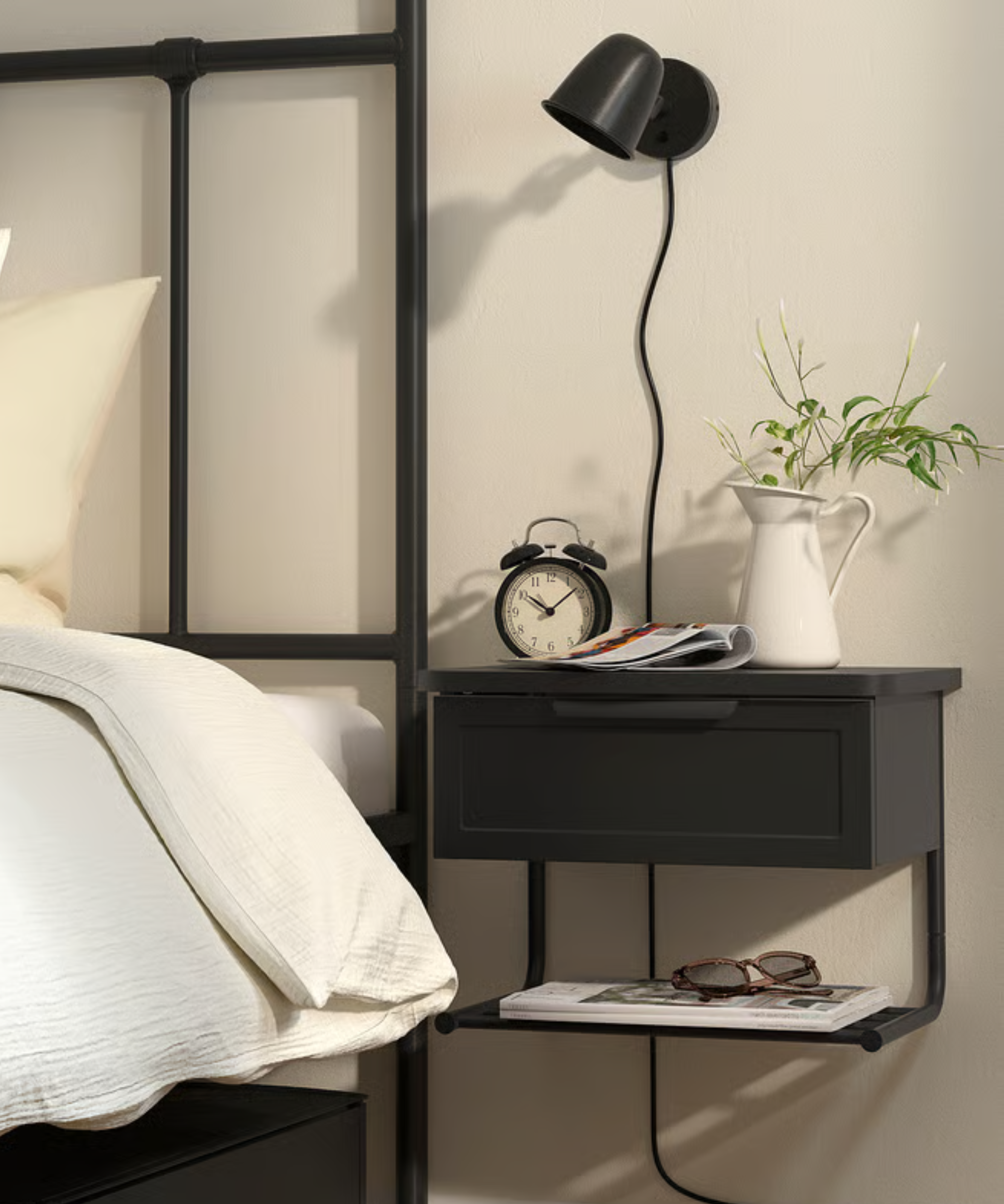 a black wall mounted nightstand next to a bed from IKEA