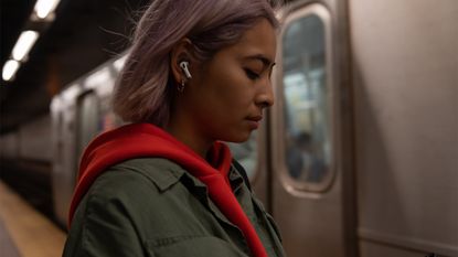 Woman on subway platform wearing Apple AirPods
