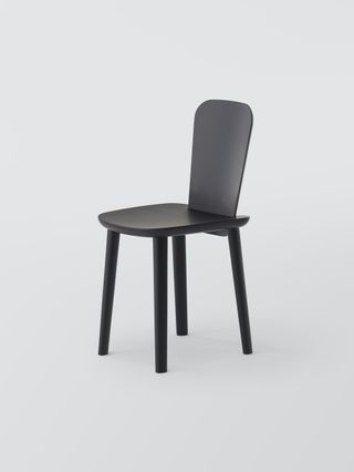 A black wooden chair with four legs connected to the base. A thin tall back, which is smaller in width than the base.
