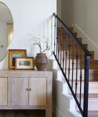 A staircase with a black railing next to an entryway console table