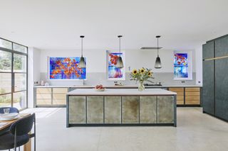 white kitchen with crittal doors, white topped kitchen island, white floor tiles, artwork, stained glass windows, dining table
