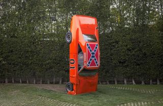 A red car nose down featuring the Confederate Flag on its roof