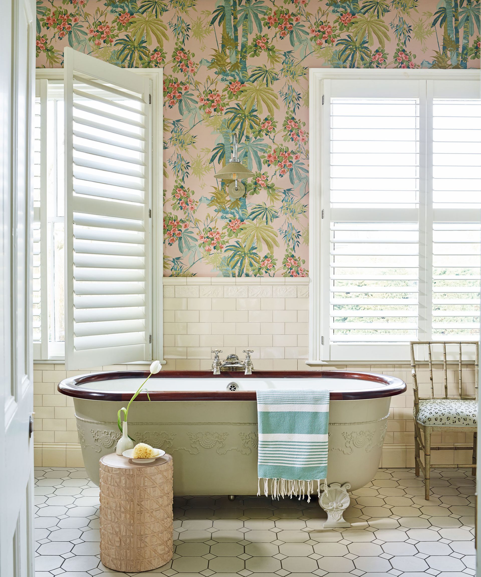 bathroom with palm print wallpaper, shutters and freestanding bath