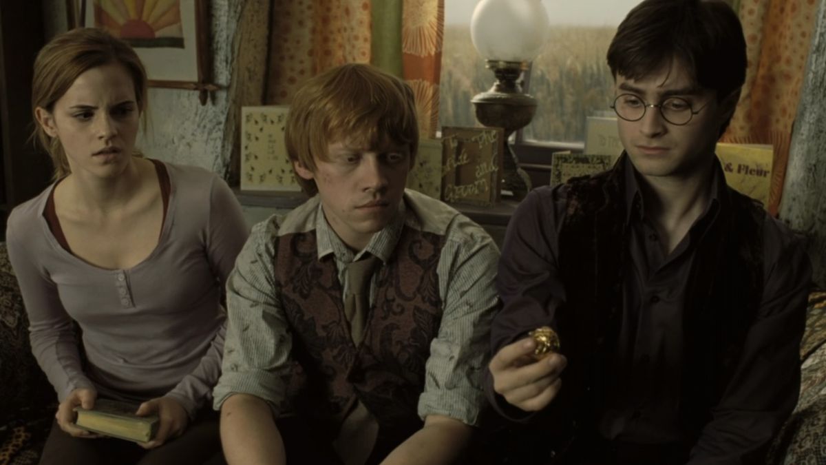 Hermione, Ron and Harry sitting together while Harry holds a snitch