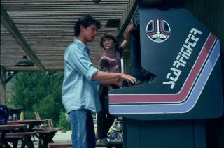A teenage boy plays an arcade video game named Starfighter