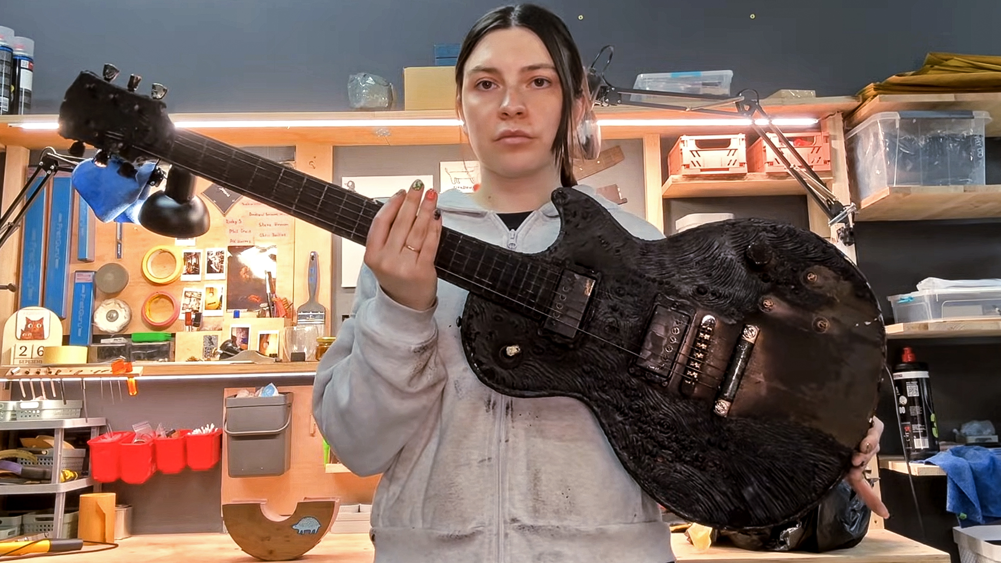 A luthier from Tadyka Guitar Repair un Ukraine holds a Les Paul guitar damaged in a drone strike and subsequently repaired 