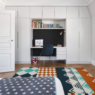 Bedroom with built in desk space and floor to ceiling wardrobes, parquet flooring and colourful rug. Pub Orig James and Jessica Straun's renovated city apartment in a Victorian apartment block in Putney, London.