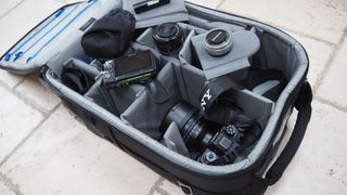 Think Tank Airport International V3.0 travel case open and filled with camera gear on a stone floor