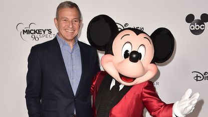 Bob Iger and a fully grown adult dressed in a Mickey Mouse costume 