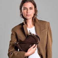 Model holding a chocolate brown suede handbag sold at Dune