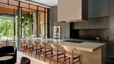 Large open plan kitchen with dark modern cabinets and a large stone islands with seating