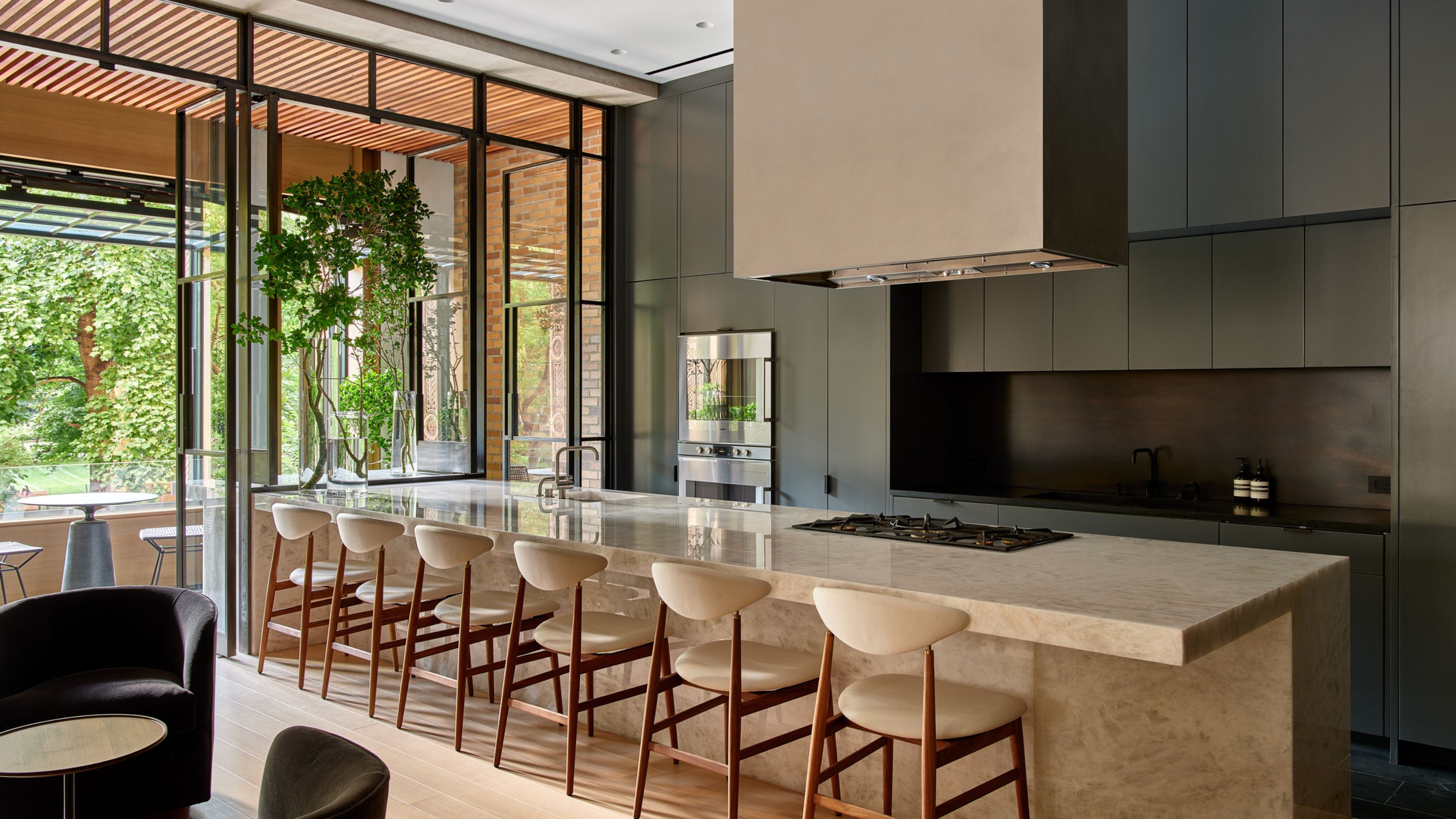 Large open plan kitchen with dark modern cabinets and a large stone islands with seating