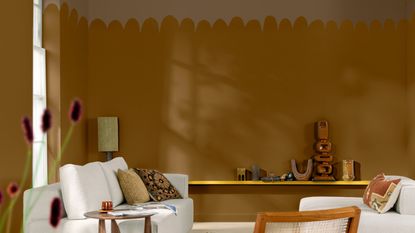 A living room with cream sofas and brown-painted walls with an irregular scalloped effect painted by hand