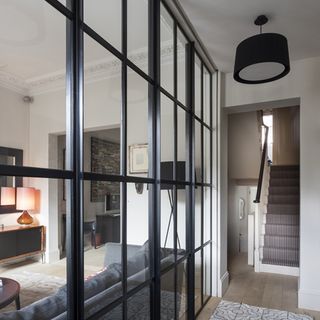 glass wall with black frame white wall steps and lamps