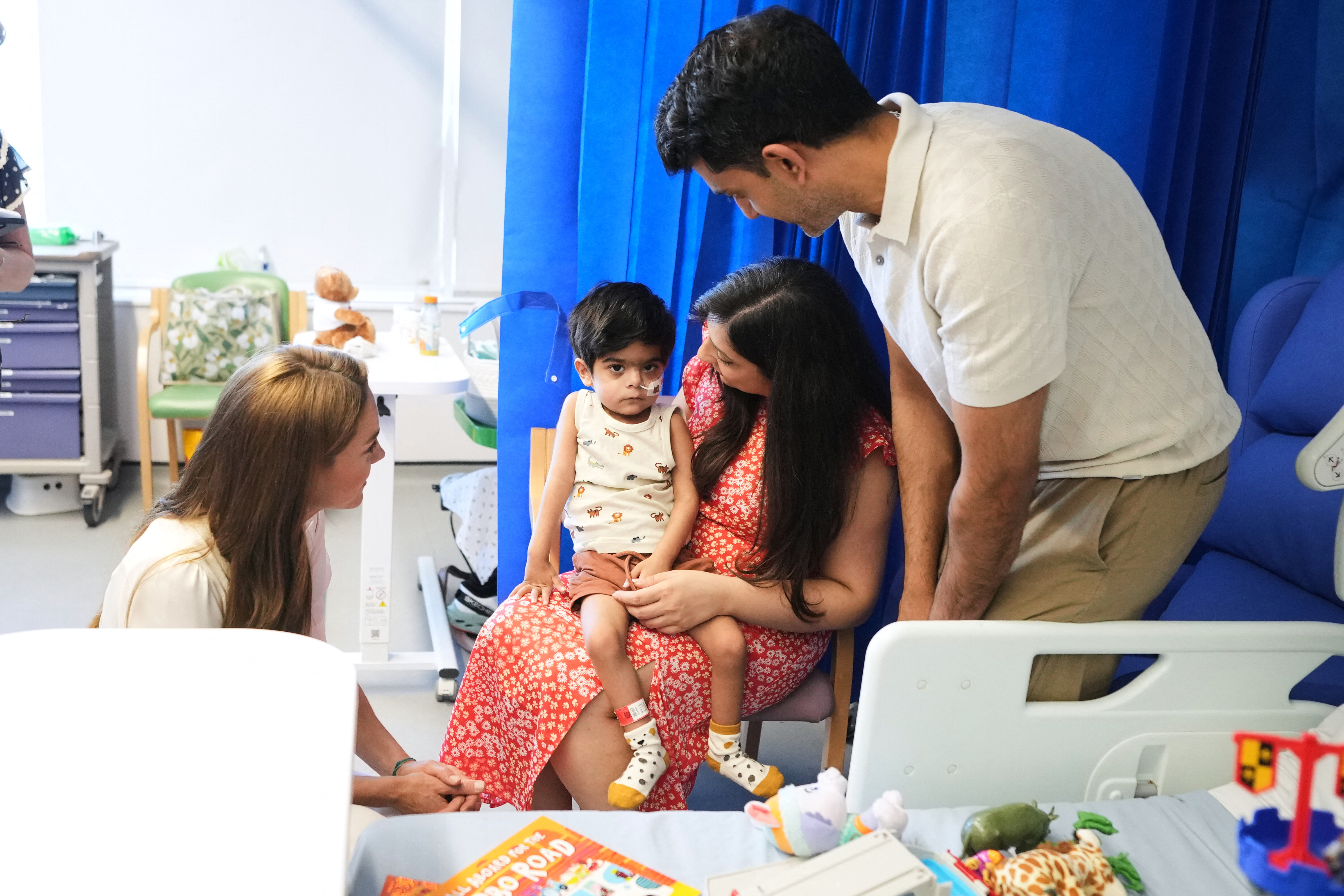 Princess Kate kneeling down in a hospital to talk to a little boy and his parents