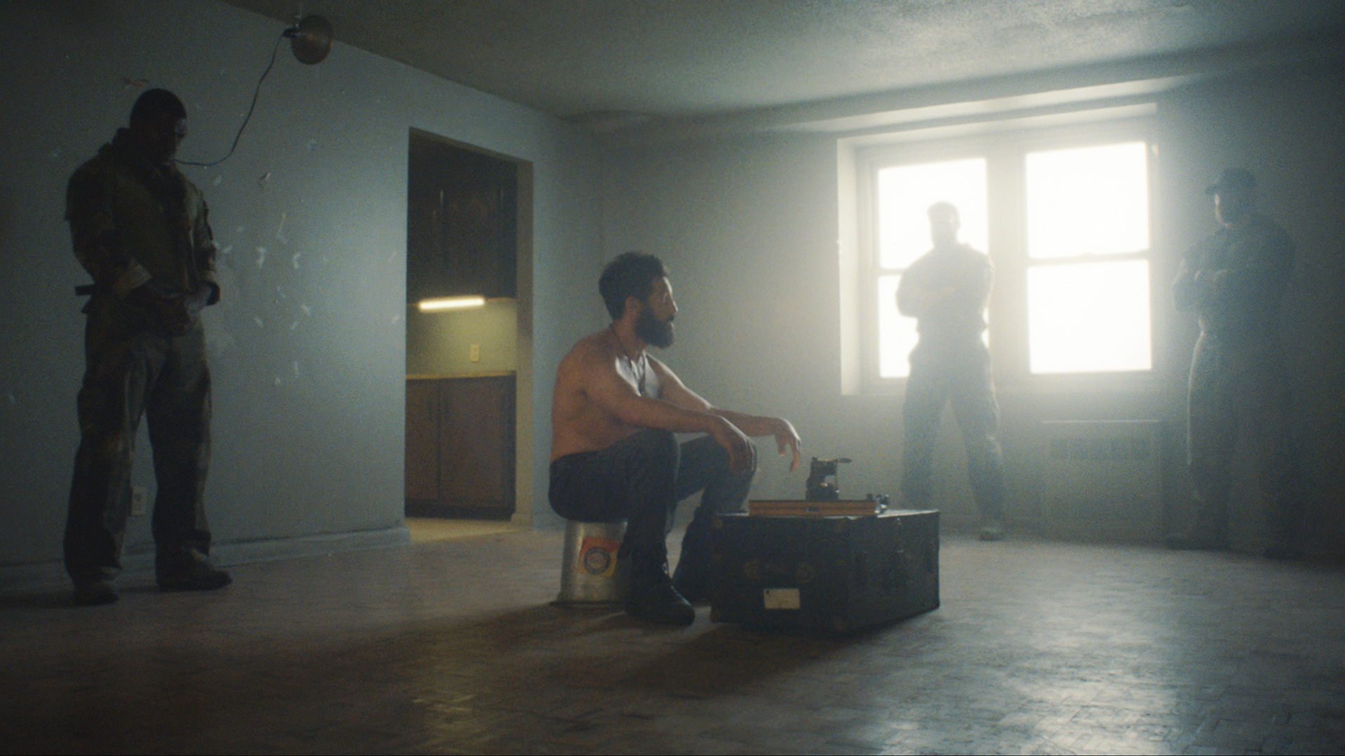 A half-naked Frank Castle sitting in a room with three men looking at him in The Punisher: One Last Kill