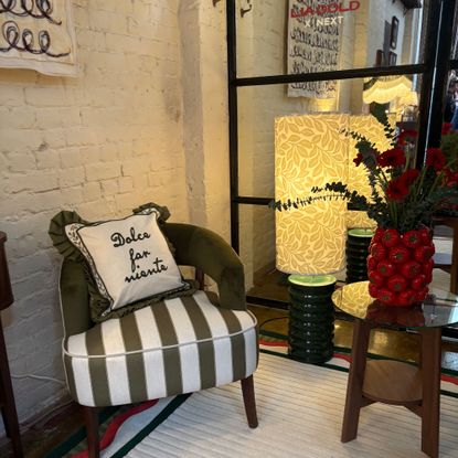 Green stripe seat with green cushion and green floor lamp and red tomato vase