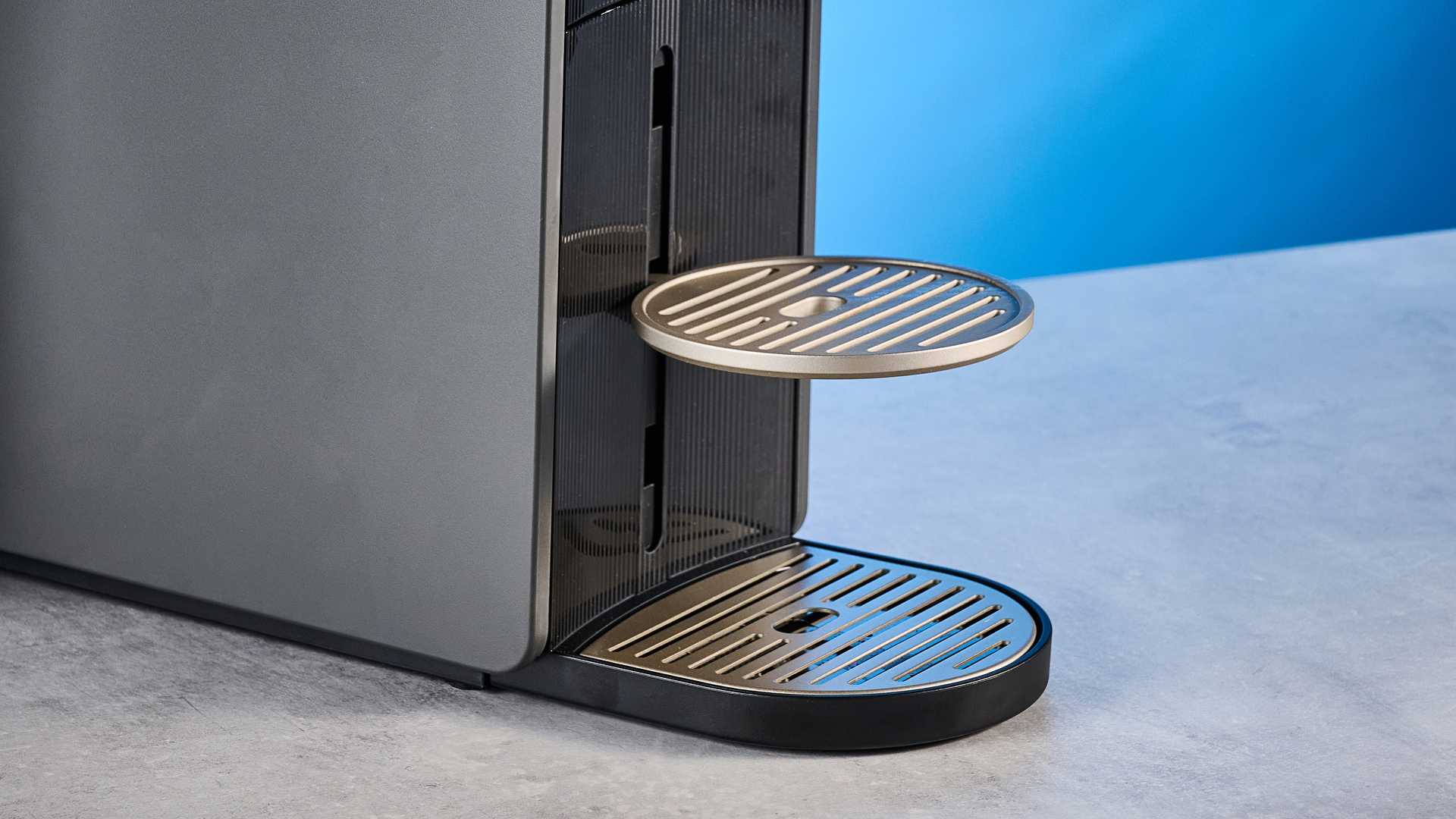 the nespresso vertuo up machine photographed against a blue background