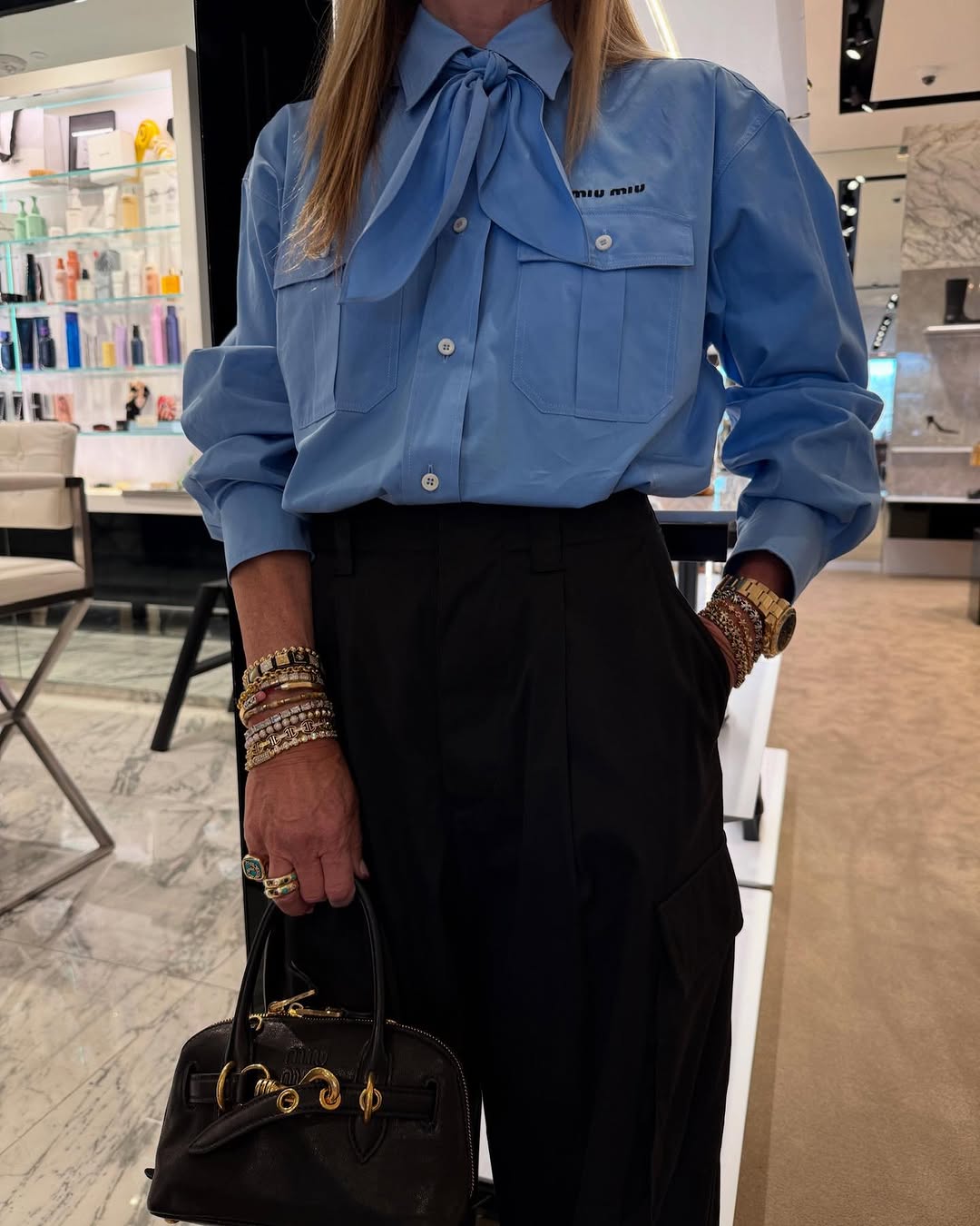 Una mujer que lleva una camisa azul con pantalones negros mostrando sus joyas.