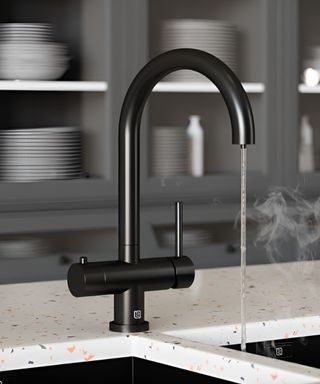 A black kitchen sink with boiling water and a terrazzo countertop