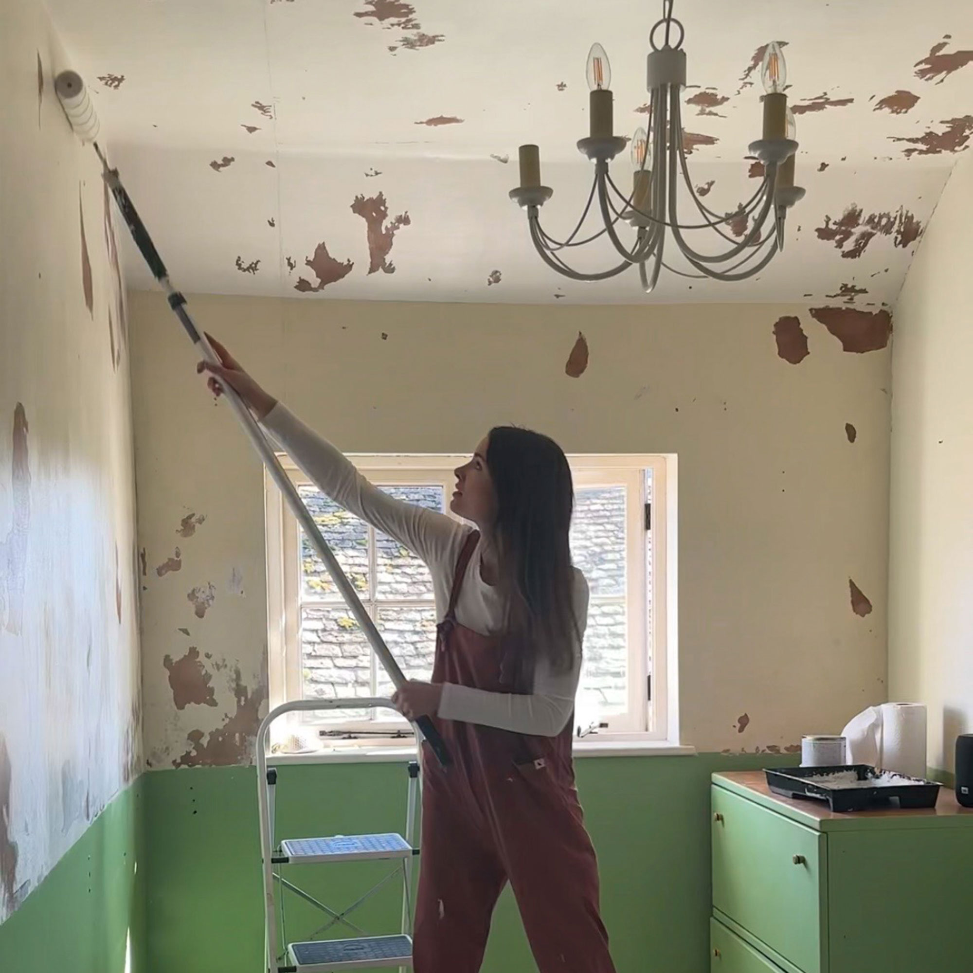 Woman painting white wall in room