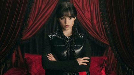 Jenna Ortega as Wednesday, standing with her arms crossed.