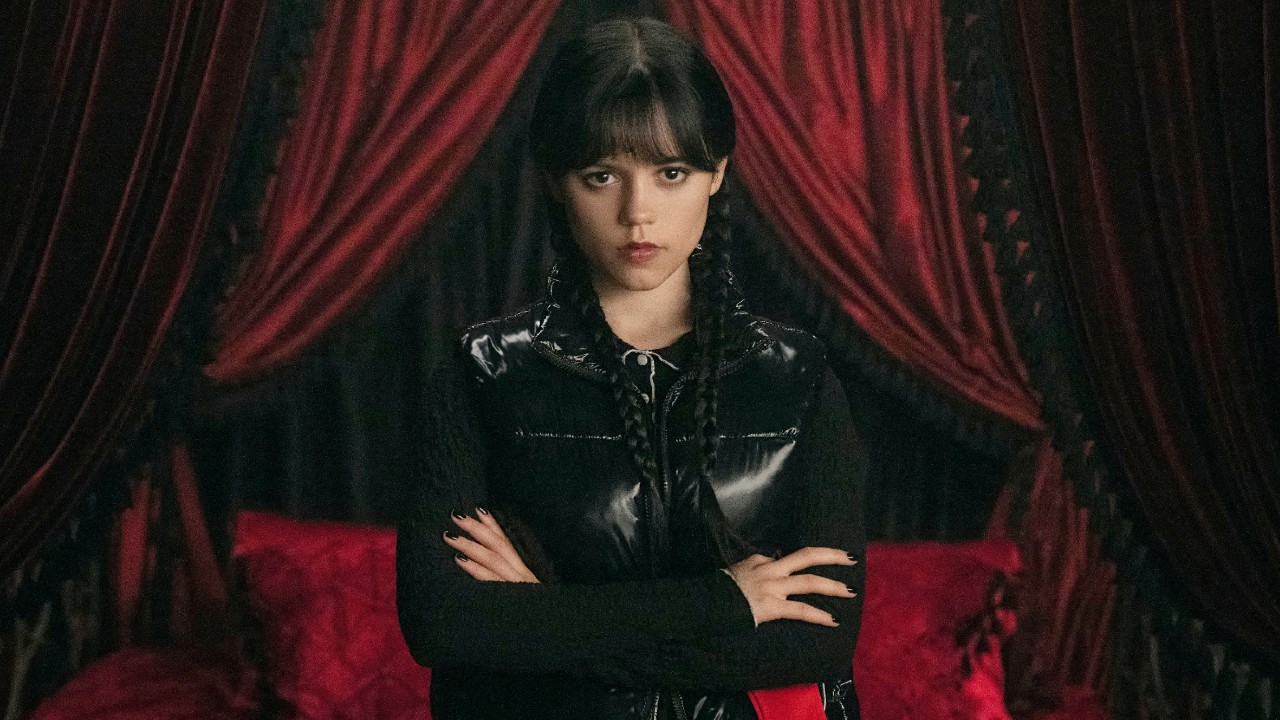 Jenna Ortega as Wednesday, standing with her arms crossed. 