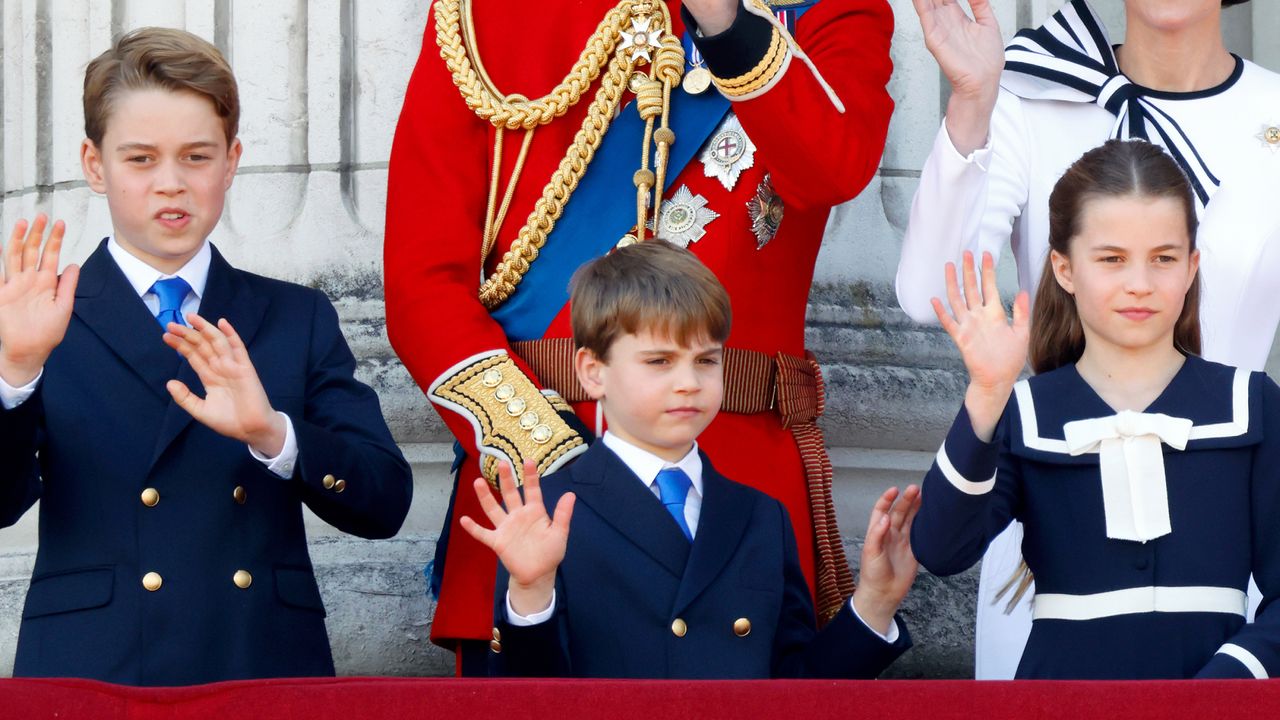 Prince George, Prince Louis and Princess Charlotte wearing navy suits and a dress waving on the Buckingham Palace balcony