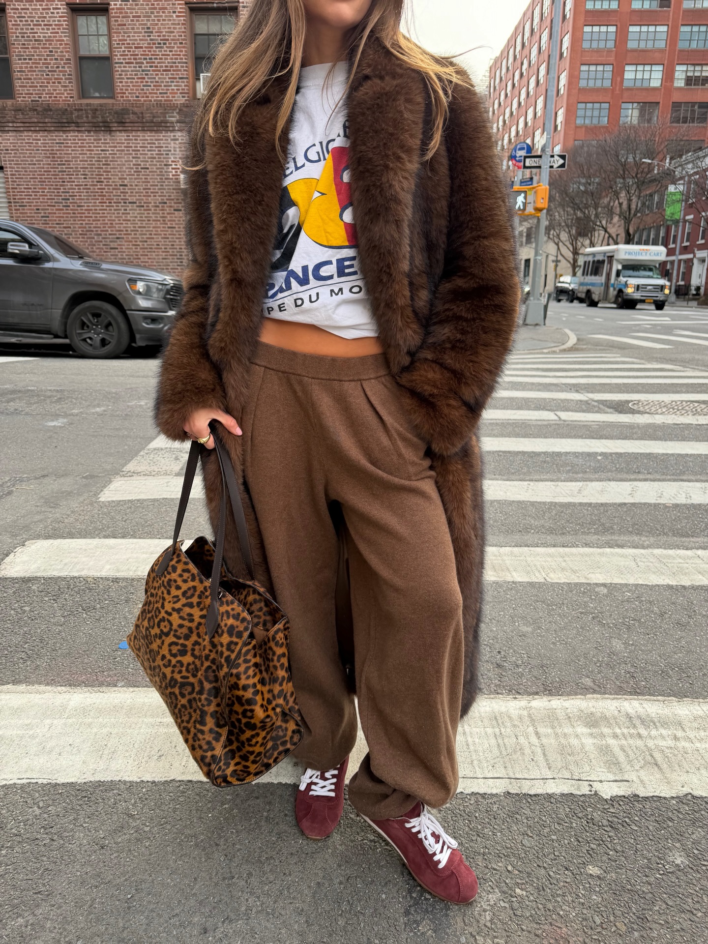 Woman wearing baggy brown pants and burgundy sneakers.