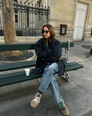 @deborabrosa wears beige suede trainers with jeans whilst sitting on a park bench