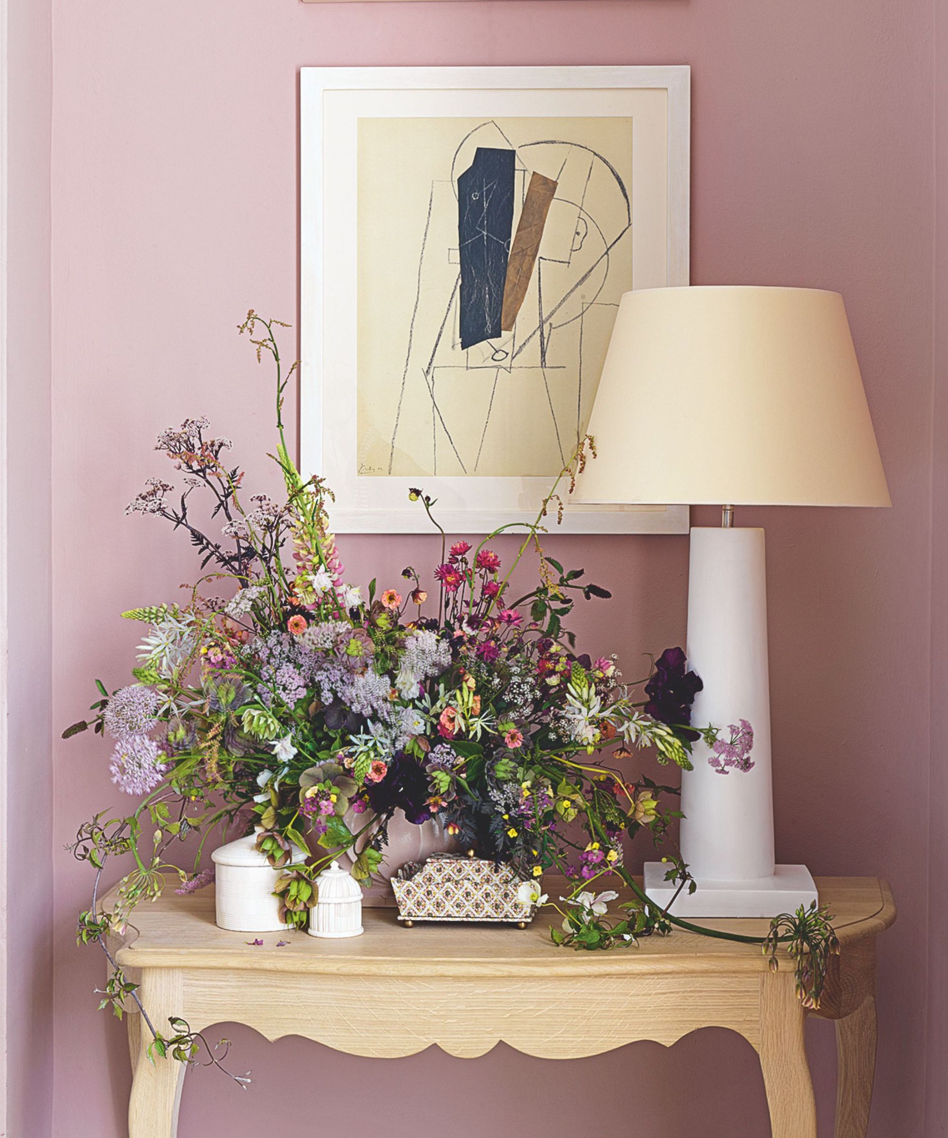 pretty floral arrangement with purple and pink theme on a console table against a soft pink wall