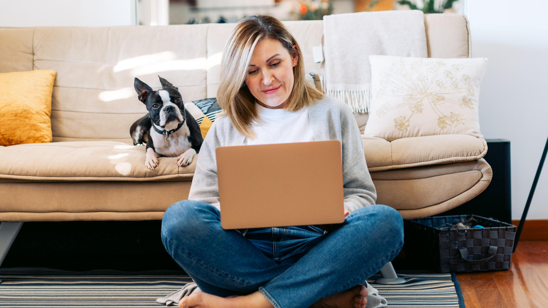 Woman sat beside sofa using laptop