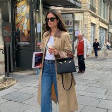 French influencer @leasy_inparis wearing a tan canvas jacket, white T-shirt, blue jeans, and Hermès handbag in Paris