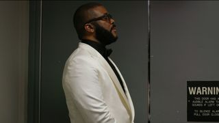 Tyler Perry standing next to a door in Maxine’s Baby: The Tyler Perry Story