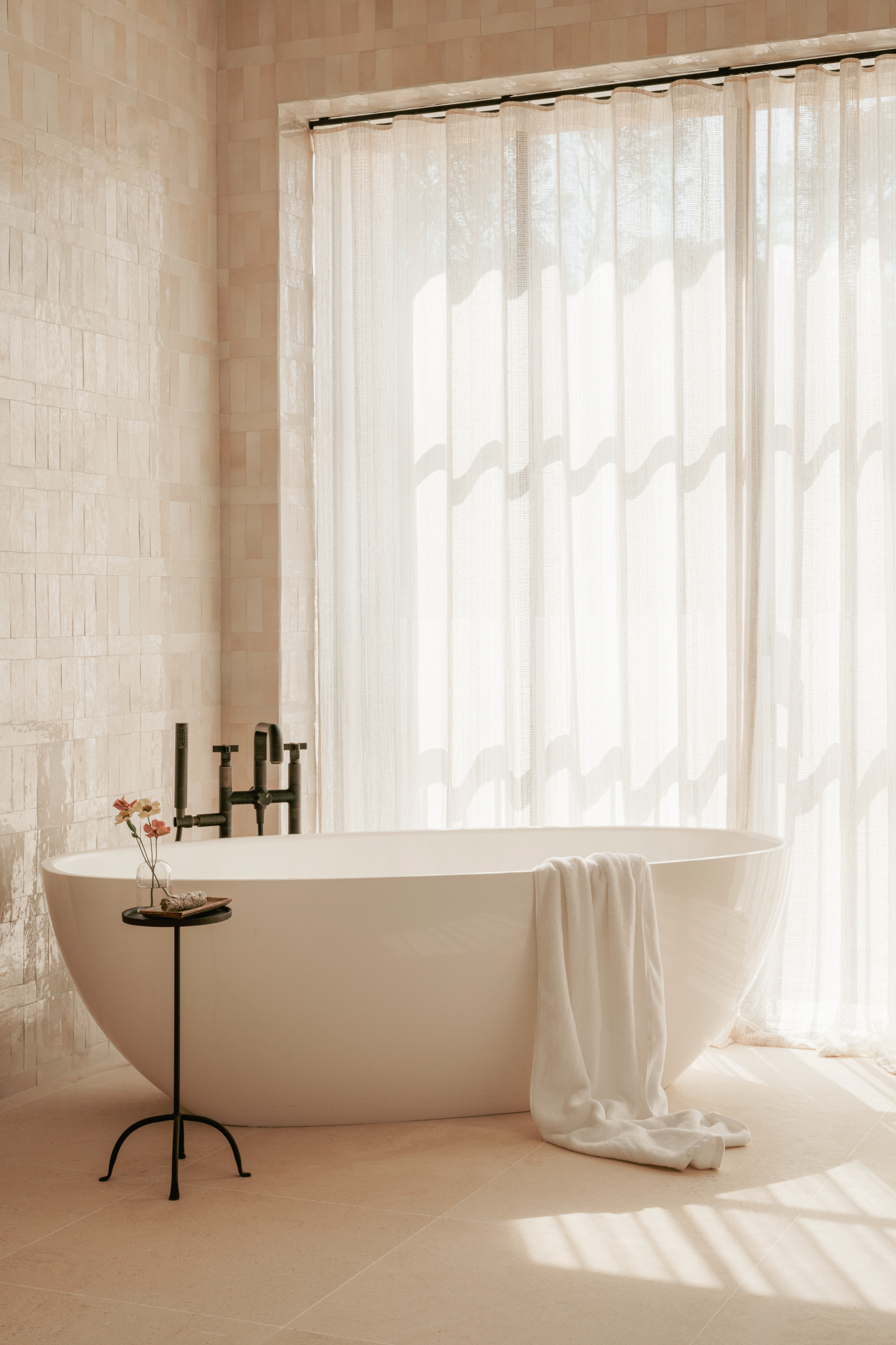 Beige bathroom with finger-tiled walls and modern freestanding tub