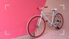 white and red bike against contrasting pink colored wall 