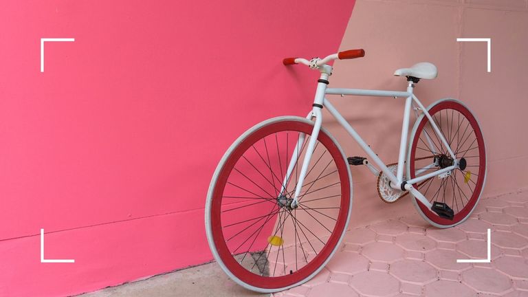 white and red bike against contrasting pink colored wall